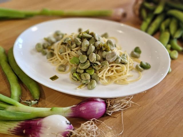 piatto di spaghetti con fave, cipollotto e aglio fresco