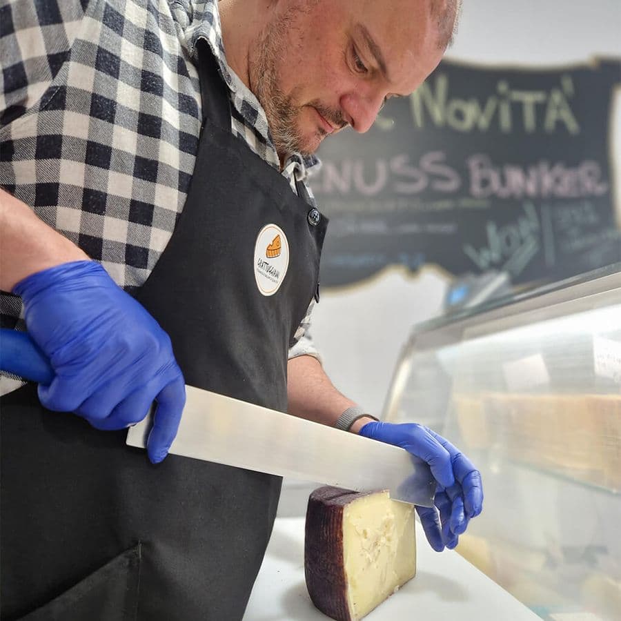 Lavoratore dell'azienda Grattuggiami che taglia il formaggio